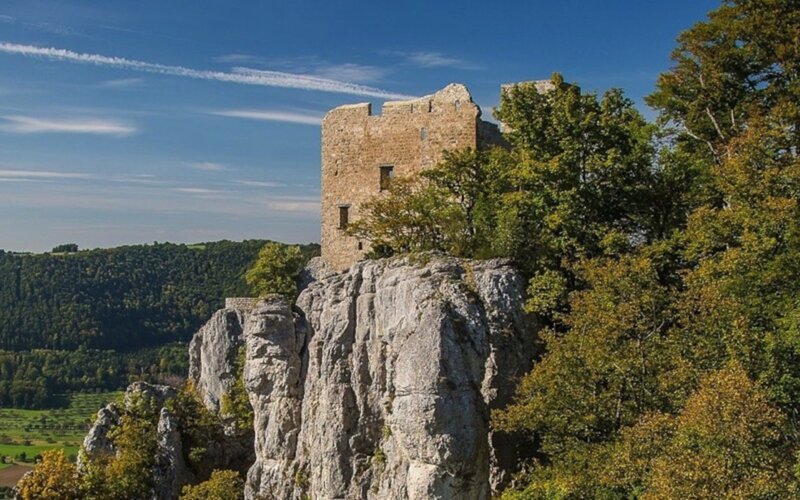 Burgruine auf einem Felsen über einem bewaldeten Tal der Schwäbischen Alb